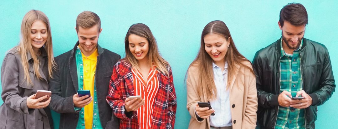 Un gruppo di persone in piedi con i loro smartphone in mano e che si divertono online